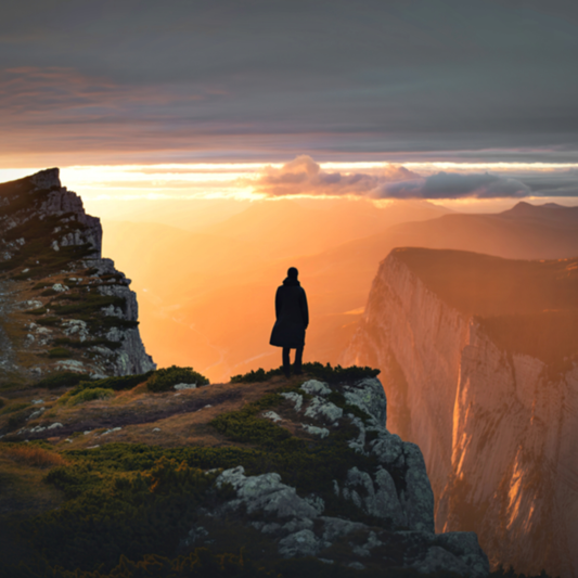 Woman standing at the edge of a cliff looking out across the horizon