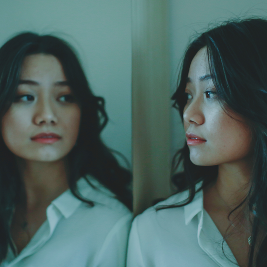Woman looking reflectively at her image in a mirror